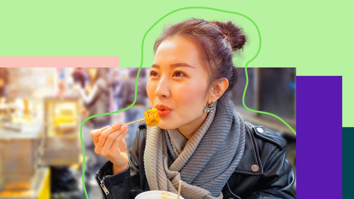 Chinese woman eating dumplings in the streets of Hong Kong