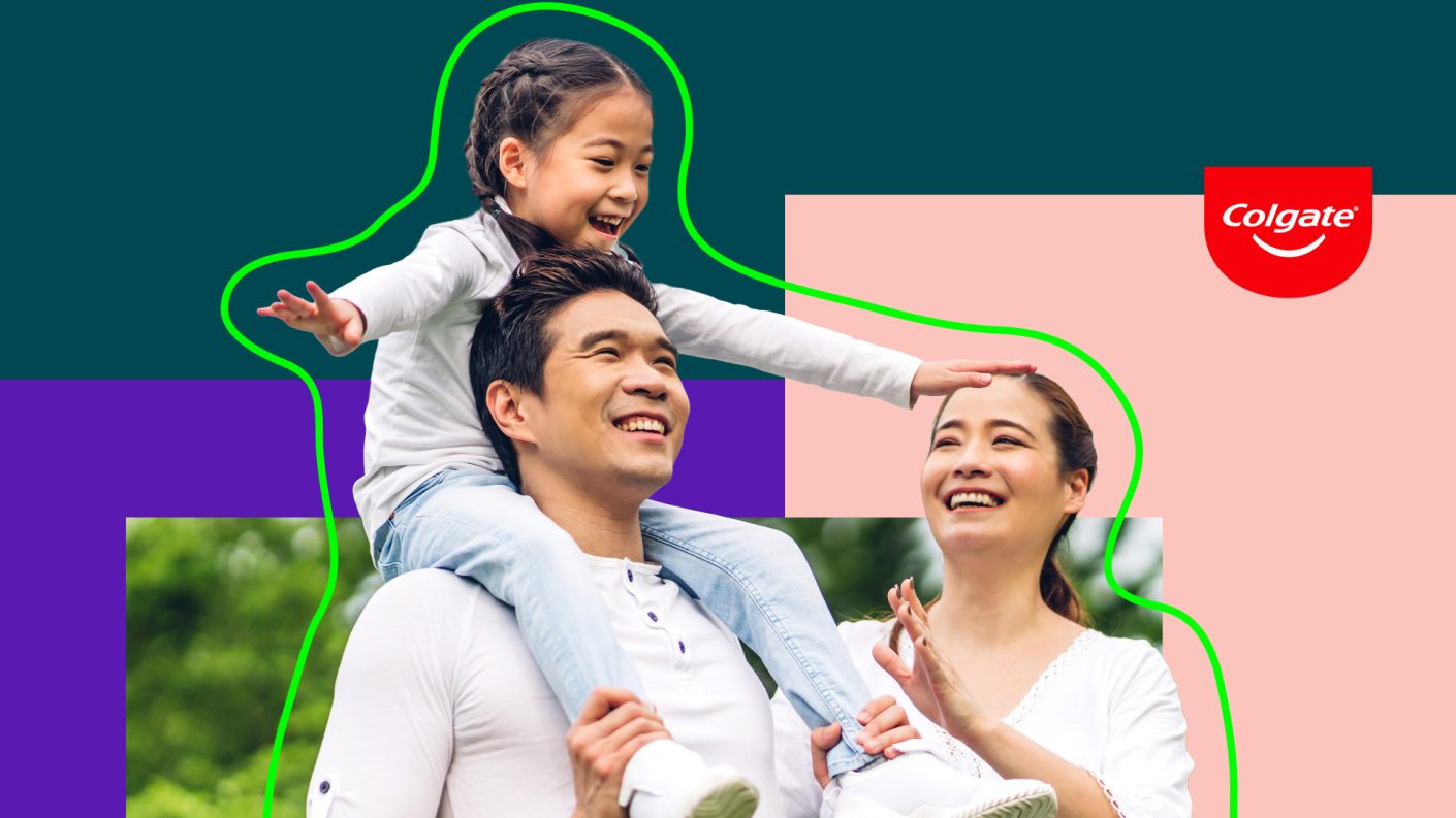 Father, mother and child smiling. Child sits on dad's shoulder pretending to be a plane.