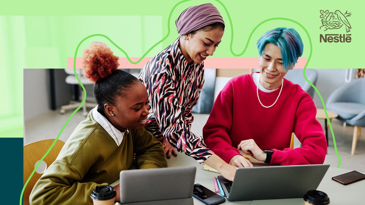 Three diverse people collaborating on an open laptop.