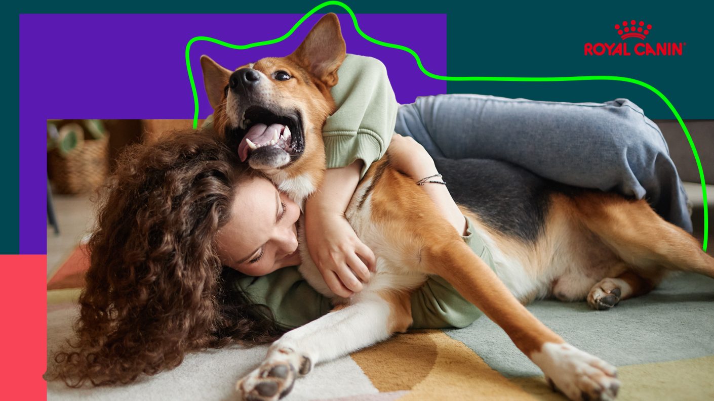 Young woman cuddling on the ground with her arm over her dog