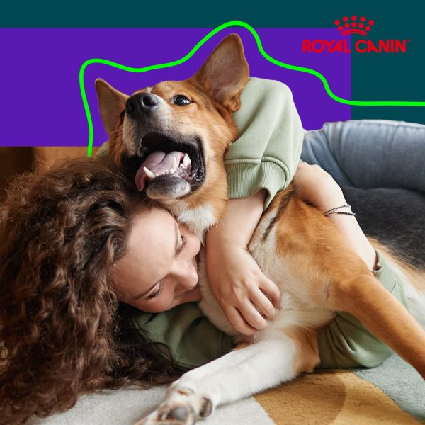 Young woman cuddling on the ground with her arm over her dog