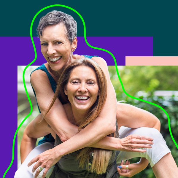 Two women having fun, one sits on the back of the other one.