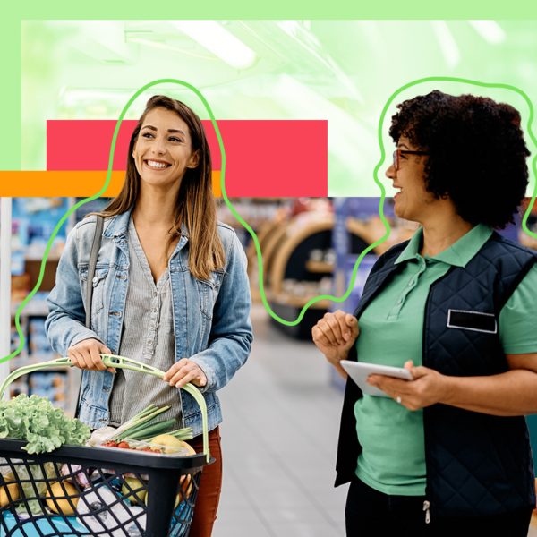 A woman carrying a shopping basket in the grocery store talking to a female employee.