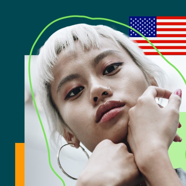 Woman looking straight at the camera with a flag of the United States behind her