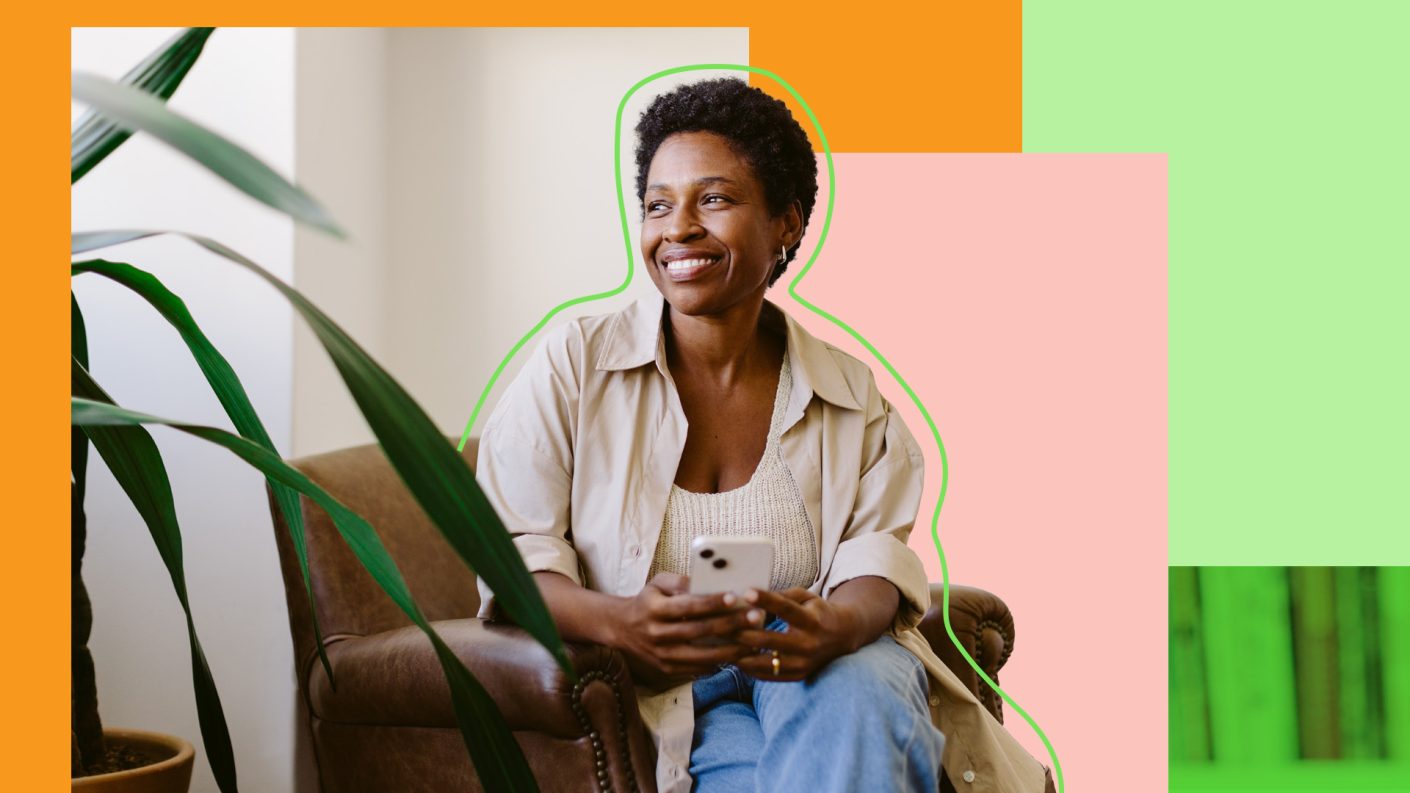 Woman smiling and sitting in a chair holding a smartphone.