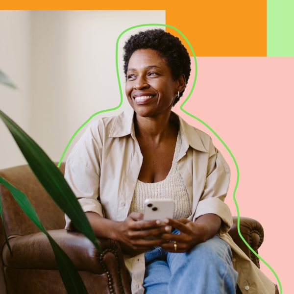 Woman smiling and sitting on a chair holding a smartphone.